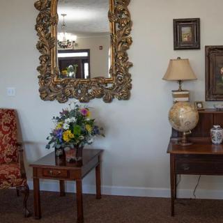 A vintage-style living room with an ornate mirror, wooden furniture, and elegant decor.