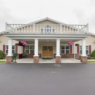 A building with a prominent entrance featuring columns and decorative hanging plants.