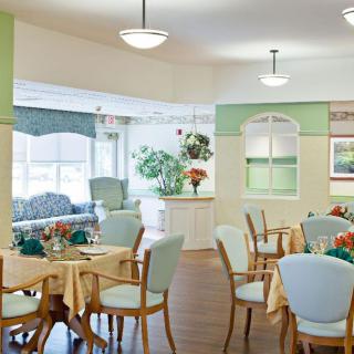 A well-lit dining area with tables, chairs, and decorative elements including plants and flowers.