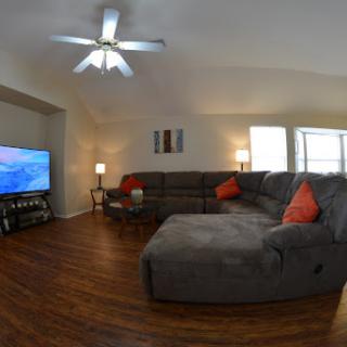 A cozy living room featuring a comfortable sectional sofa, a television, and warm lighting.