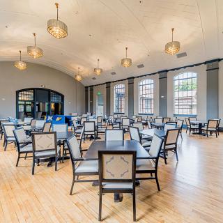 Spacious dining area with tables and chairs, featuring large windows and elegant lighting.