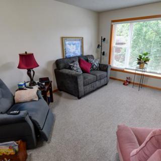 A cozy living room with a sofa, armchair, and large window.