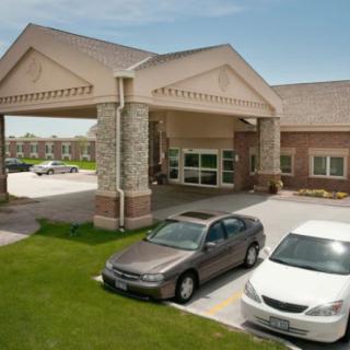 A building entrance with parked cars in front during the daytime.