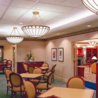 A well-lit room with tables and chairs, featuring elegant chandeliers and decorative elements.