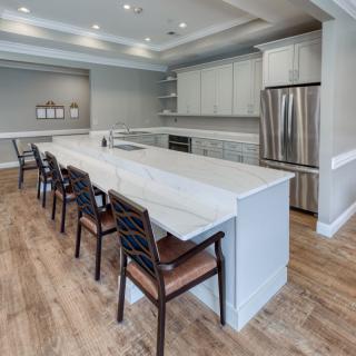 A modern kitchen featuring a large island with bar stools, stainless steel appliances, and wood flooring.