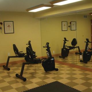 A small gym with several exercise bikes and mirrors on the wall.