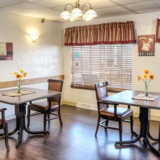 A cozy dining area with wooden tables and chairs, decorated with flowers.