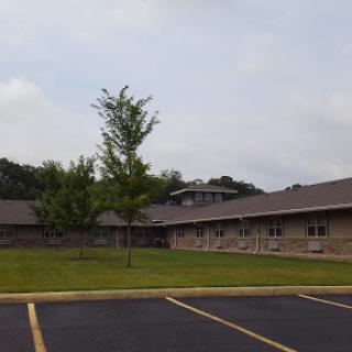A view of a residential building surrounded by trees and a parking lot.