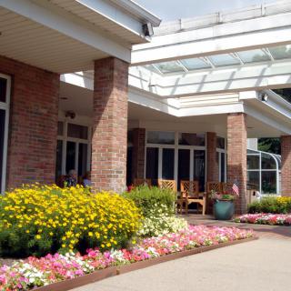 A well-landscaped building entrance with brick pillars and colorful flowerbeds.