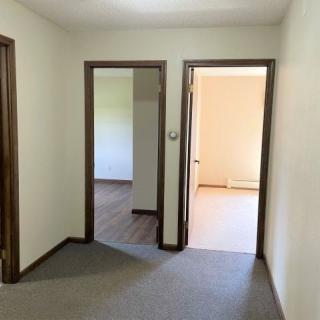 A hallway in an apartment with multiple open doors leading to empty rooms.