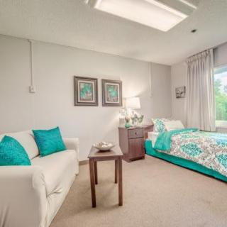 A modern bedroom with teal accents, featuring a comfortable bed, sofa, and tasteful decor.