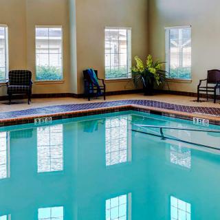 Indoor swimming pool with surrounding chairs and large windows.