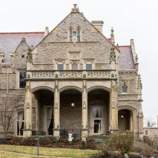 A grand, historic mansion with intricate stone architecture and a spacious porch.