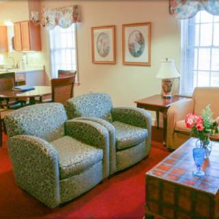 Cozy living room with a pair of armchairs, a sofa, and a coffee table adorned with flowers.