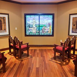 A cozy waiting area featuring ornate chairs, vibrant artwork on the walls, and a beautiful stained glass window.
