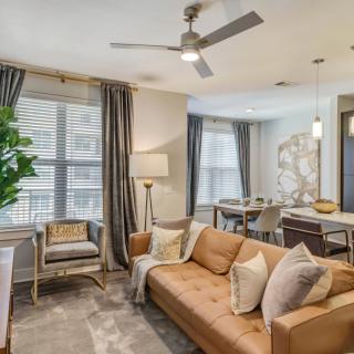 A modern living room with a cozy sofa and dining area, featuring neutral tones and stylish decor.