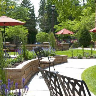 A scenic outdoor garden area with paved walkways, seating, and umbrellas offering a peaceful setting.
