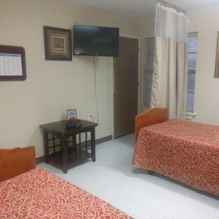 A cozy hotel room featuring two beds, a television, and warm decor.