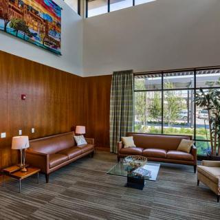 A modern living room with leather sofas, a coffee table, and large windows.