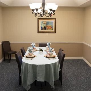 A neatly arranged dining room with a table set for four, illuminated by a chandelier and adorned with wall art.