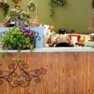A cozy reception area with decorative plants and a wooden counter.