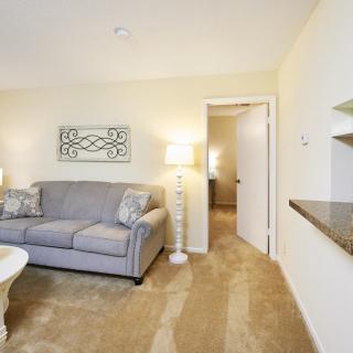A cozy living room featuring a gray sofa, a floor lamp, and a decorative wall piece.