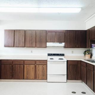 A spacious kitchen with wooden cabinets and white appliances.