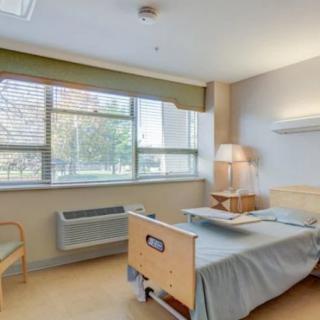 A clean and well-lit hospital room with a bed and large window.