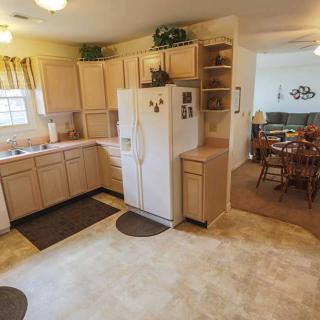 A cozy kitchen with wooden cabinets and a white refrigerator, leading to an adjoining dining area.