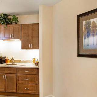 A cozy kitchen corner with wooden cabinets and a framed painting on the wall.
