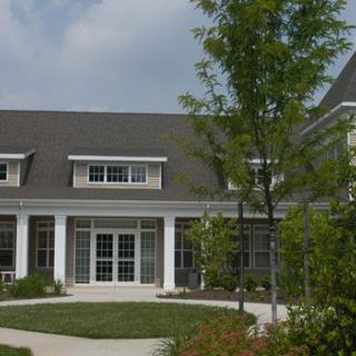 A residential house with a garden and trees in front.
