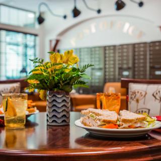 A cozy restaurant table setting with a sandwich and drinks.