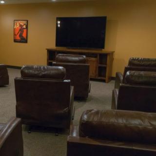 Cozy home theater with leather seating and a large screen for viewing.