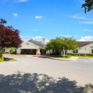 A bright, sunny day at a residential or community building with surrounding trees and a driveway.