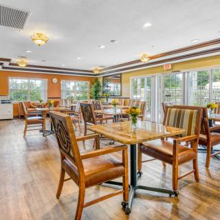 A spacious dining area with wooden tables and chairs, well-lit by large windows.