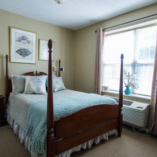 A cozy bedroom with a four-poster bed and large window.