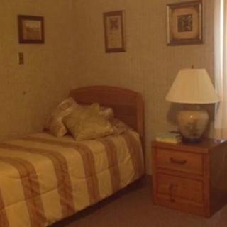 A cozy bedroom with a single bed, nightstand, and lamp.