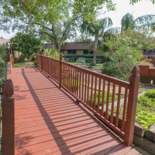 A serene wooden bridge overlooking a lush garden area with surrounding trees and plants.