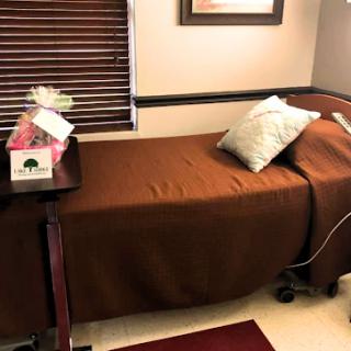 A cozy hospital room featuring a neatly made bed with a brown blanket and decorative pillow.
