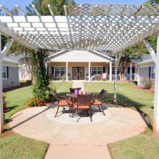 A charming backyard with a pergola and outdoor seating area, surrounded by a well-maintained lawn.