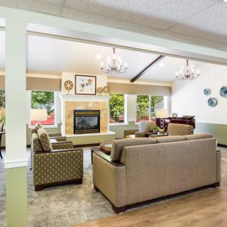 A cozy living room with comfortable sofas and a fireplace, featuring large windows and tasteful decor.