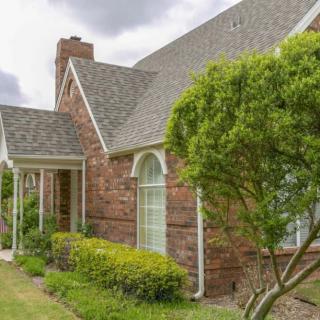 A charming brick house with a well-maintained garden and large windows.