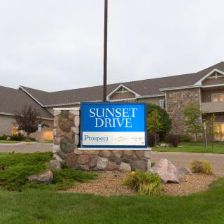 A sign for Sunset Drive Apartments in front of a residential building.