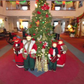 A festive Christmas tree surrounded by holiday decorations indoors.