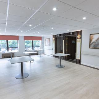 A spacious, well-lit conference room featuring modern tables and a minimalist design.