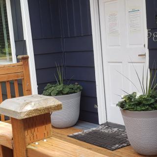 A house entrance with a wooden deck and planters flanking the doorway.