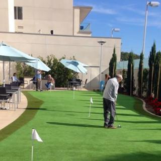 People enjoying a game on the outdoor putting green under clear blue skies.
