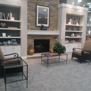 A cozy living room with a central fireplace, surrounded by shelves and comfortable chairs.