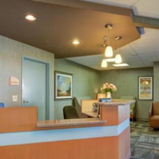 A reception area featuring a desk, chairs, and wall art in a modern office setting.