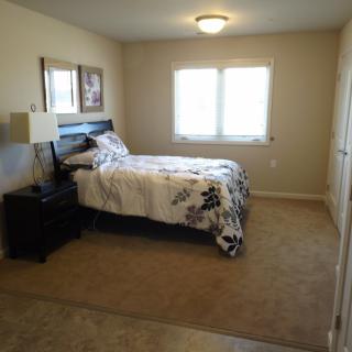 A cozy bedroom with a bed, nightstand, and carpeted floor.